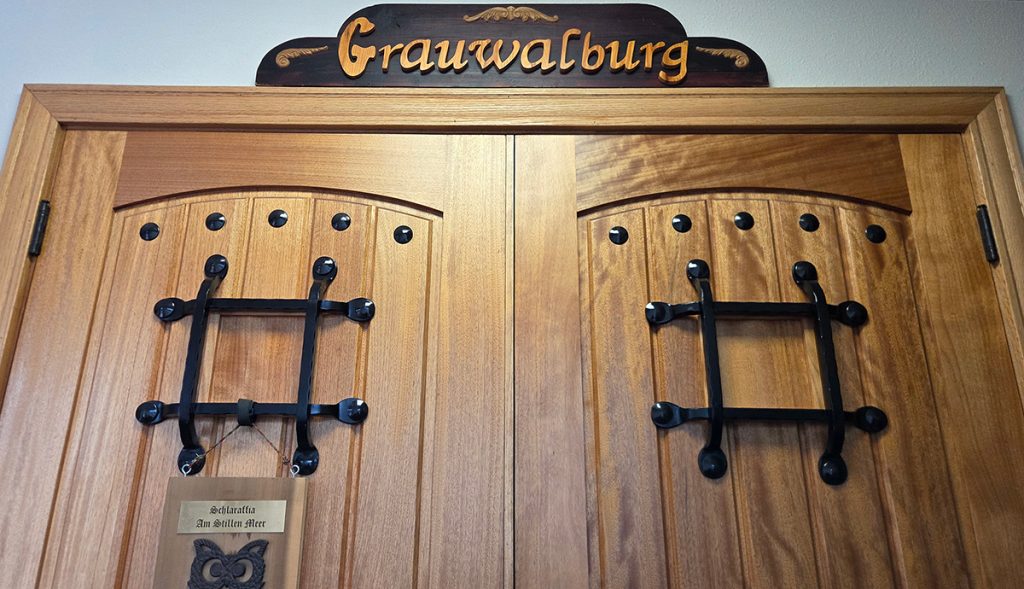 Wooden doors with Grauwalburg sign at the unique Grey Whale Castle event venue in San Diego